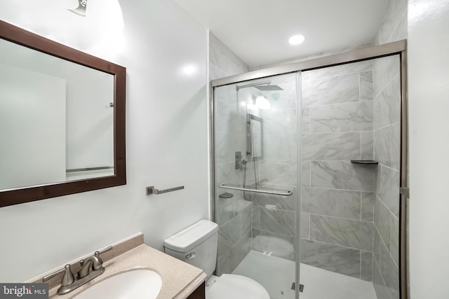 bathroom featuring vanity, toilet, and a shower with shower door