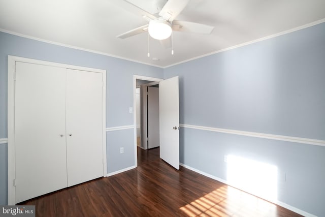 unfurnished bedroom featuring ceiling fan, a closet, dark hardwood / wood-style floors, and ornamental molding