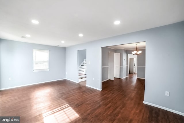 empty room featuring a chandelier and dark hardwood / wood-style flooring