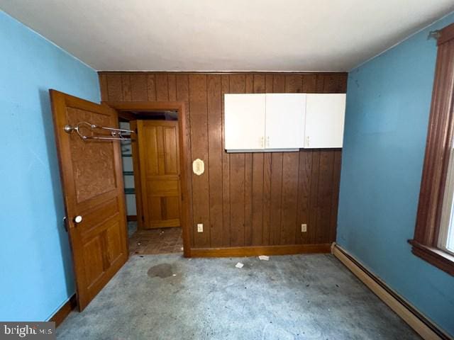 spare room with wooden walls and a baseboard heating unit