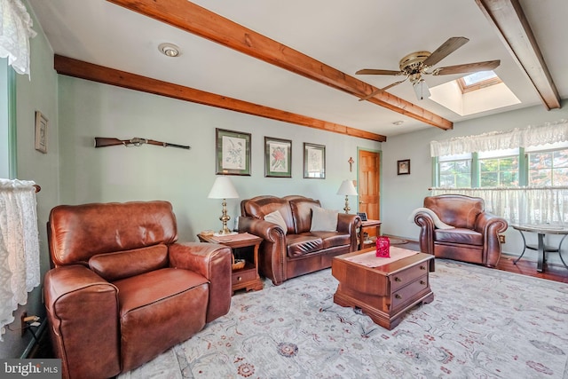 living room featuring beam ceiling, a skylight, and ceiling fan