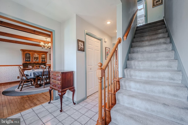 staircase with tile patterned flooring and an inviting chandelier