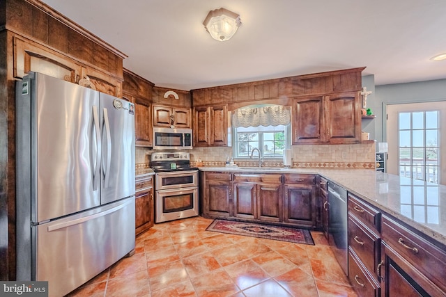 kitchen featuring sink, stainless steel appliances, light stone counters, decorative backsplash, and light tile patterned flooring