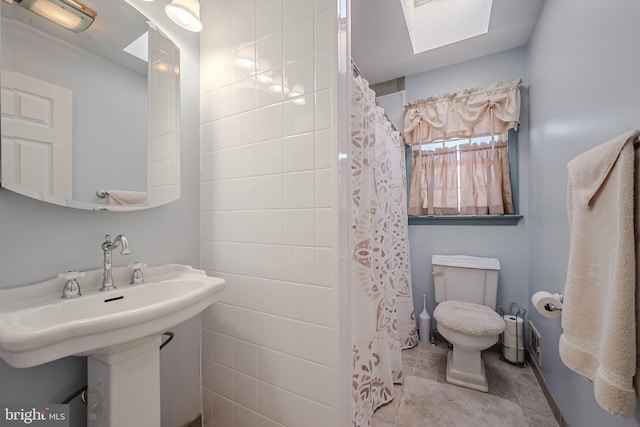 bathroom featuring a skylight, sink, and toilet