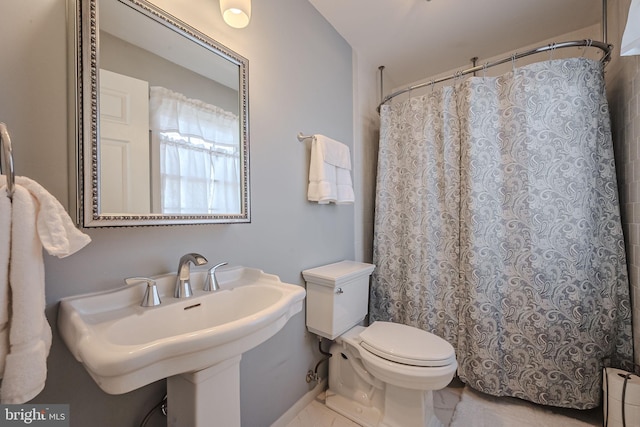 bathroom with a baseboard radiator, toilet, curtained shower, and sink