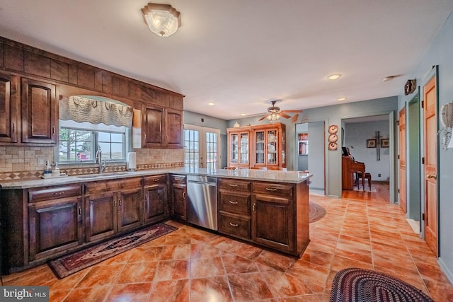 kitchen featuring kitchen peninsula, tasteful backsplash, stainless steel dishwasher, and sink