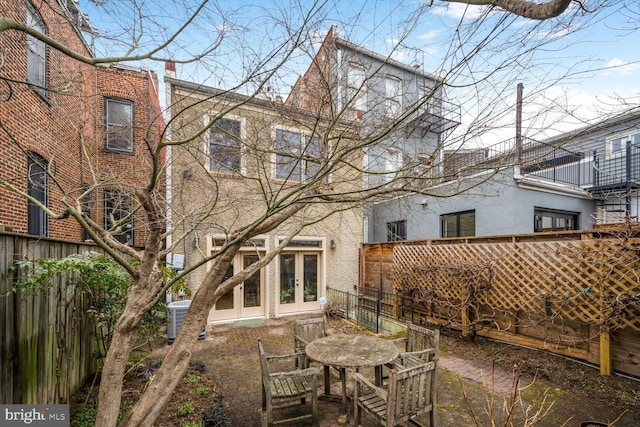 rear view of property featuring central air condition unit, french doors, a fenced backyard, and stucco siding