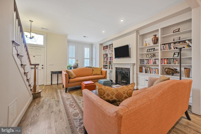 living room with crown molding, wood finished floors, a fireplace, and visible vents