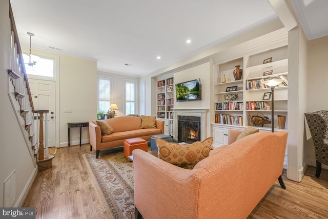 living room with stairway, wood finished floors, visible vents, and ornamental molding