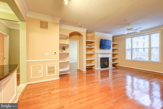 unfurnished living room featuring ceiling fan, light hardwood / wood-style floors, ornamental molding, and a textured ceiling