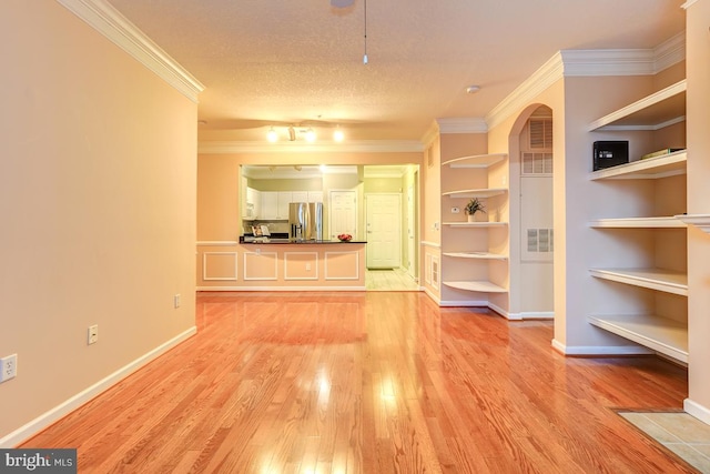 living room featuring built in shelves, crown molding, light hardwood / wood-style flooring, and a textured ceiling