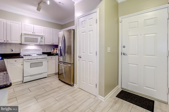 kitchen featuring white appliances, backsplash, rail lighting, crown molding, and white cabinetry