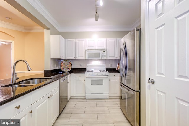 kitchen with tasteful backsplash, stainless steel appliances, sink, dark stone countertops, and white cabinetry