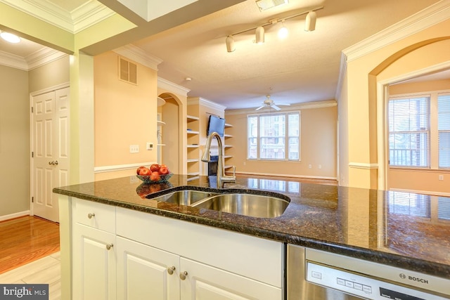 kitchen with dark stone countertops, white cabinetry, stainless steel dishwasher, and sink