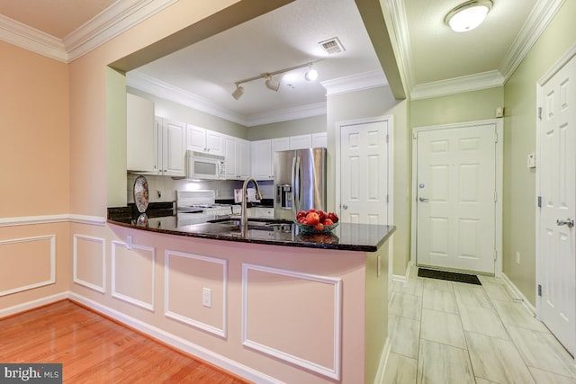 kitchen with dark stone counters, sink, kitchen peninsula, stainless steel fridge with ice dispenser, and white cabinetry