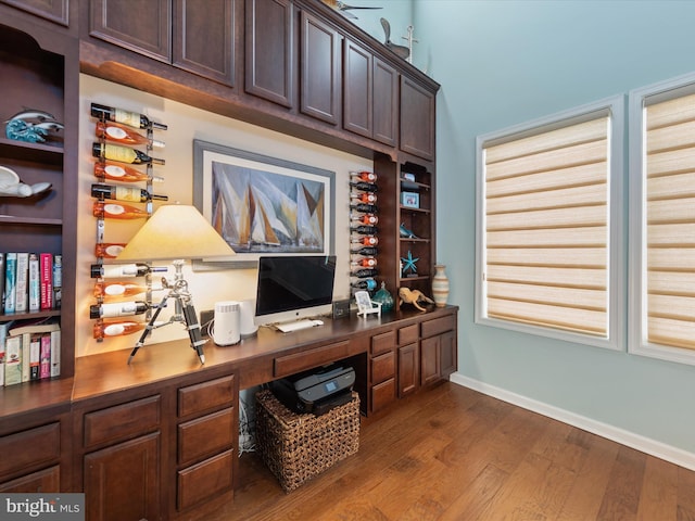 home office with dark hardwood / wood-style floors and built in desk