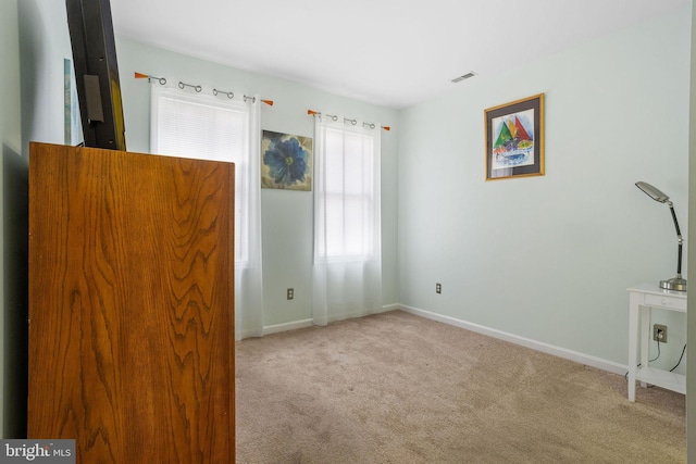 unfurnished bedroom featuring light colored carpet and multiple windows