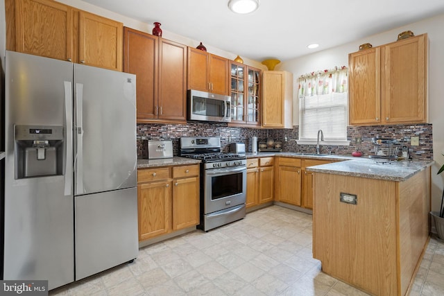 kitchen with kitchen peninsula, decorative backsplash, stainless steel appliances, and sink