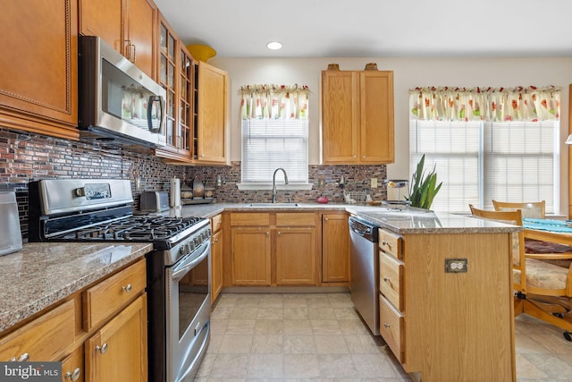 kitchen with backsplash, light stone counters, sink, and stainless steel appliances