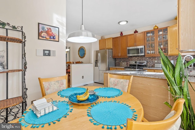 kitchen featuring kitchen peninsula, decorative backsplash, stainless steel appliances, and decorative light fixtures