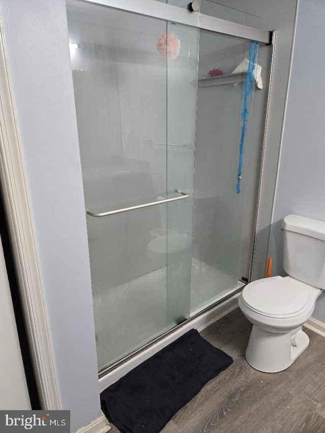 bathroom with toilet, a shower with door, and hardwood / wood-style flooring