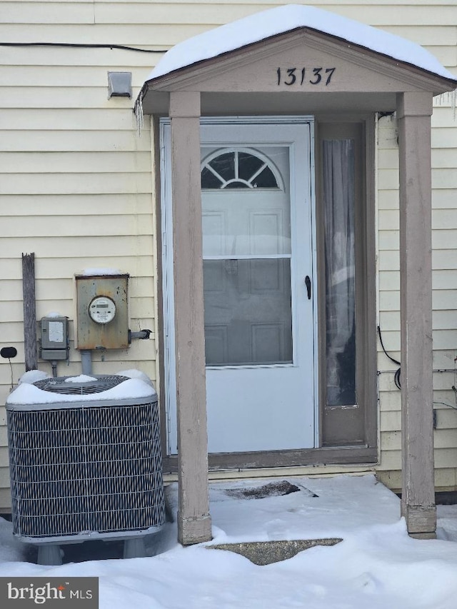 snow covered property entrance featuring cooling unit