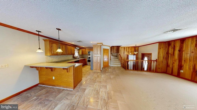 kitchen featuring visible vents, a breakfast bar area, brown cabinets, a peninsula, and hanging light fixtures