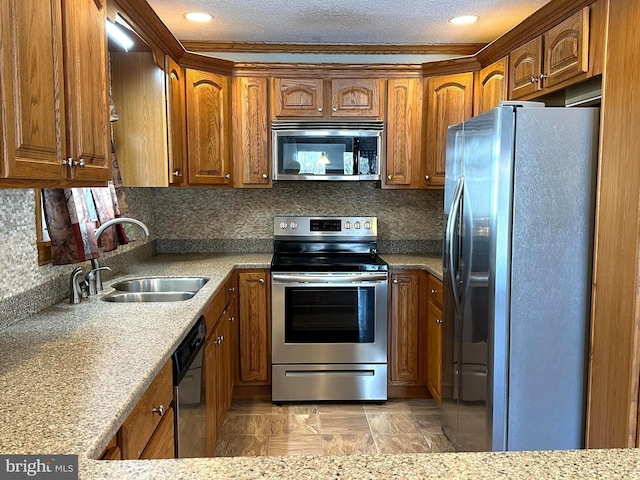 kitchen featuring appliances with stainless steel finishes, brown cabinetry, a sink, and tasteful backsplash