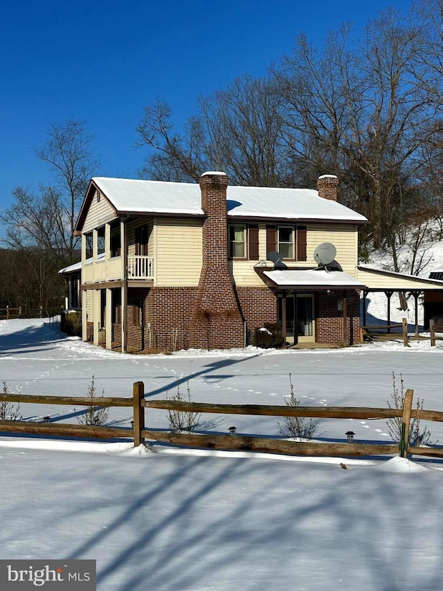 exterior space with brick siding, a chimney, and a balcony