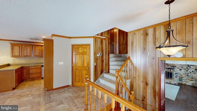 staircase featuring ornamental molding, visible vents, a textured ceiling, and baseboards