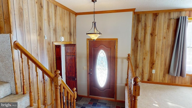 entryway featuring ornamental molding, wood walls, and baseboards