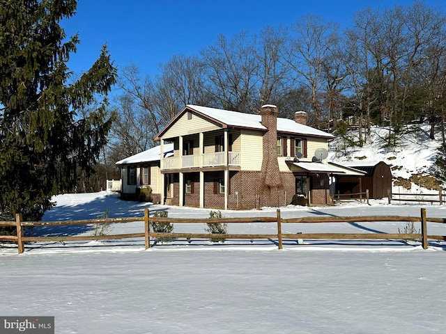 view of front of home featuring a chimney, fence, a balcony, a shed, and an outdoor structure