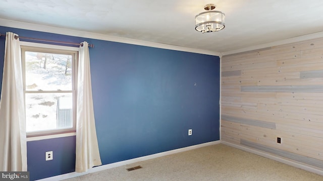 carpeted empty room with baseboards, visible vents, and wooden walls