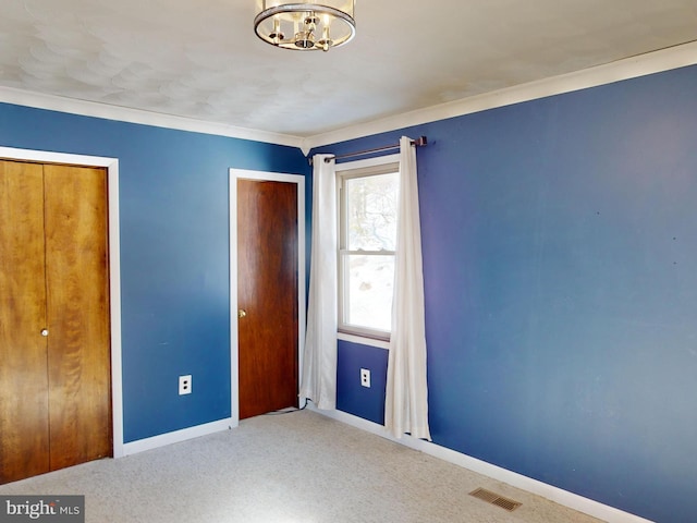 unfurnished bedroom with carpet, visible vents, baseboards, and a notable chandelier