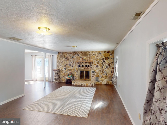 unfurnished living room with a fireplace, visible vents, dark wood finished floors, and crown molding