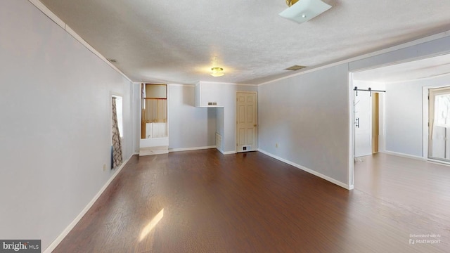 interior space with dark wood-style floors, ornamental molding, baseboards, and a barn door