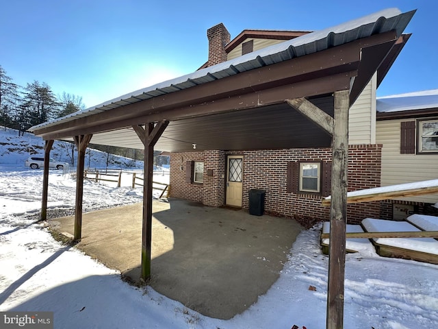 snow covered patio featuring a carport