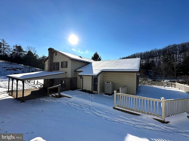 view of snowy exterior featuring cooling unit and fence