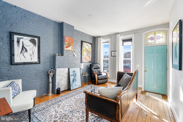 sitting room featuring brick wall and wood-type flooring