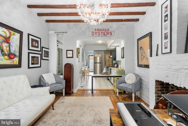 sitting room featuring a fireplace, a notable chandelier, beamed ceiling, and hardwood / wood-style floors