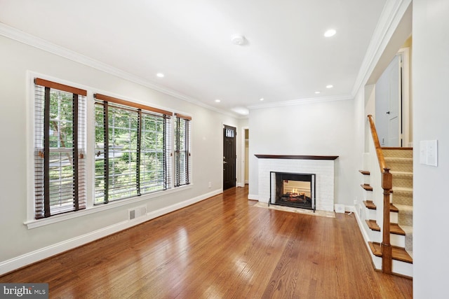 unfurnished living room with ornamental molding, a fireplace, and light hardwood / wood-style flooring