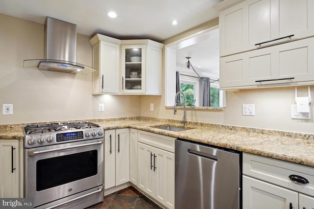 kitchen with light stone countertops, sink, stainless steel appliances, and wall chimney exhaust hood