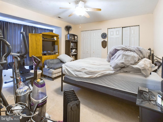 bedroom featuring carpet floors, visible vents, a ceiling fan, and multiple closets