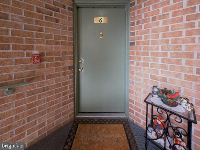 view of exterior entry featuring brick siding