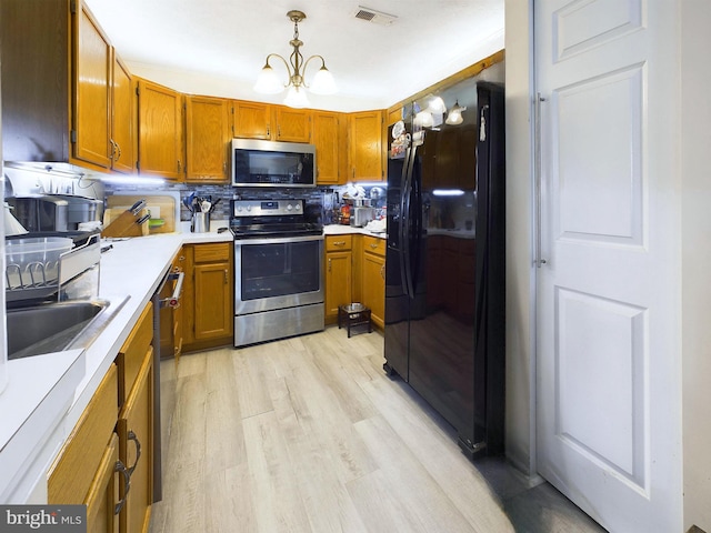 kitchen featuring stainless steel appliances, backsplash, a chandelier, pendant lighting, and light wood-type flooring