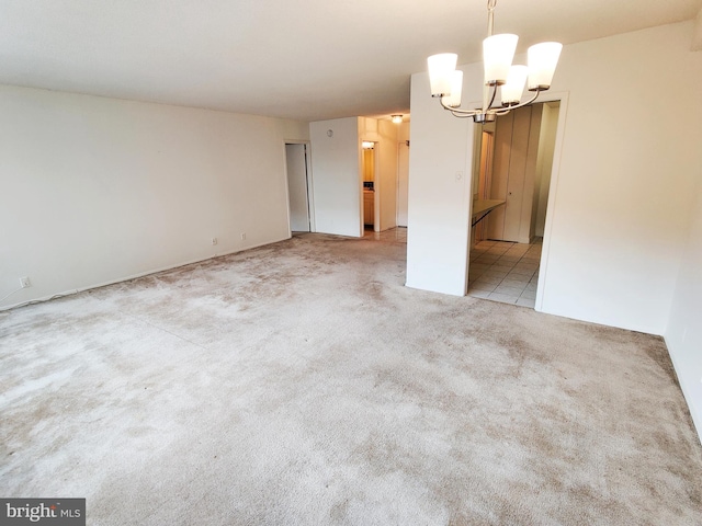 carpeted empty room with a notable chandelier