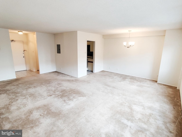 carpeted spare room featuring electric panel, a textured ceiling, and a notable chandelier