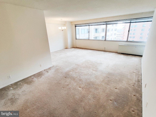 carpeted empty room with an inviting chandelier