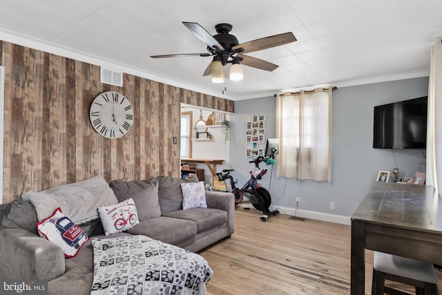 living room featuring hardwood / wood-style floors, ceiling fan, ornamental molding, and wooden walls