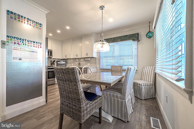 dining room with sink, dark hardwood / wood-style flooring, and ornamental molding